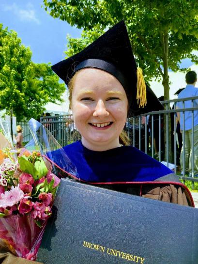 person with graduation cap, degree, and flowers