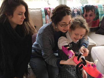 people helping small child with prosthetic arm